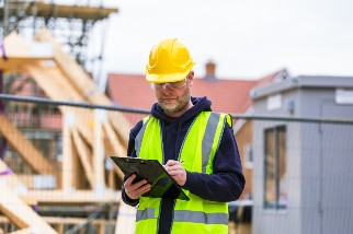 Closeup of a safety professional holding a clipboard on a construction site
