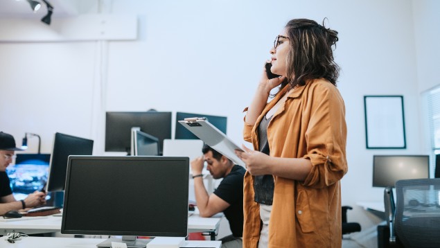 Safety professional woman holding a clipboard and talking on the phone in an office