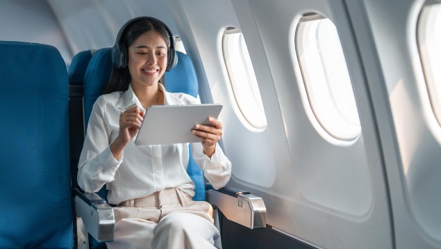 Safety professional woman using headphones and a tablet computer on a plane