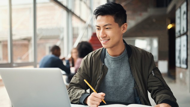 Safety student studying with a laptop and notebook in a library