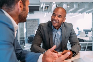 Two business leaders smiling and meeting at a conference table