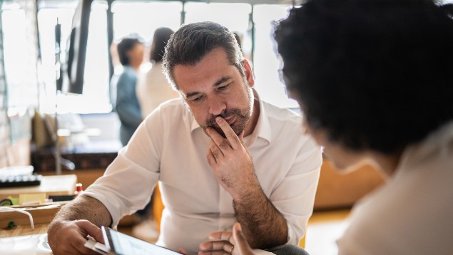 Two colleagues solving a problem by looking at a tablet