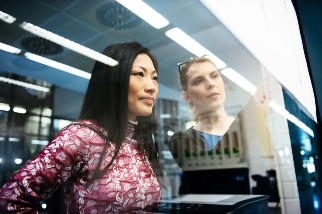 Two engineers discussing next steps while looking at documents hanging on a window