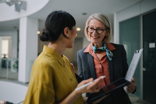 Two professional women talking in the hallway holding tablets