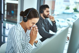 Woman in a call center sneezing beside her coworker