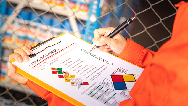 Safety professional holding clipboard with hazmat communication form
