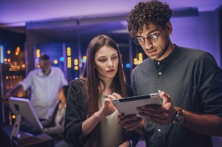 Male and female maintenance engineers examining data on digital tablet together in server room.