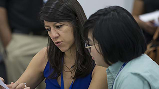 two women sitting next to each other looking at a piece of paper