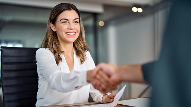 woman in business attire shaking hands at a meeting